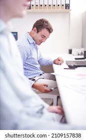 Architect Checking Cell Phone Under Desk In Office