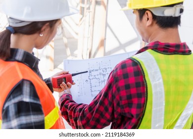 Architect And Client Discussing The Plan With Blueprint Of The Building At Construction Site. Asian Engineer Foreman Worker Man And Woman Working Talking On Drawing Paper To Checking Project