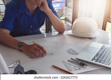 Architect or construction design concept. Young engineer working in office and using computer laptop, blueprint to design house or building. Engineering concept. - Shutterstock ID 1242617773