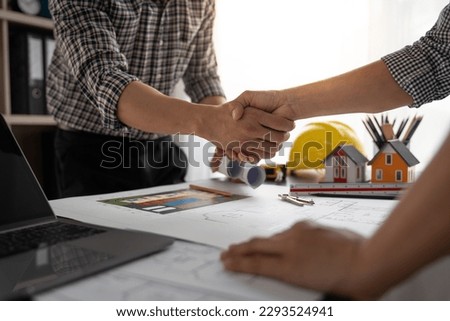 Architect and construction worker engineers shaking hands while teamwork and cooperation concept after completion of agreement on village construction project Successful Collaboration Concept.