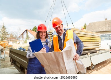 Architect And Craftsman With Architectural Drawing On Construction Site With Lumber Delivery In The Background