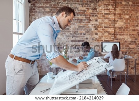 Architect, design engineer or building contractor drawing a plan on a drafting table for a project or development in his office. A male designer doing a blueprint sketch at an architecture company