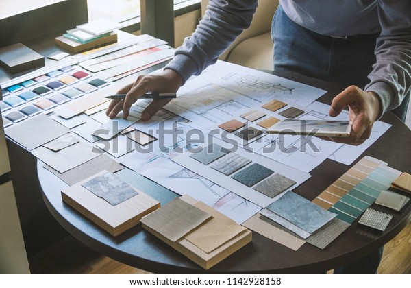 Architect designer Interior creative working hand\
drawing sketch plan blue print selection material color samples art\
tools Design Studio