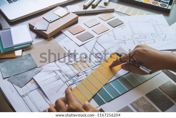 Architect designer Interior creative working hand\
drawing sketch plan blueprint selection material color samples art\
tools Design Studio