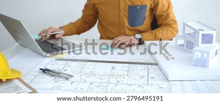 Architect developing an innovative property design from blueprints to a detailed architectural scale model, planning real estate projects and urban infrastructure development