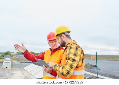 Architect Discusses Road Construction Planning With Foreman Using Tablet Computer