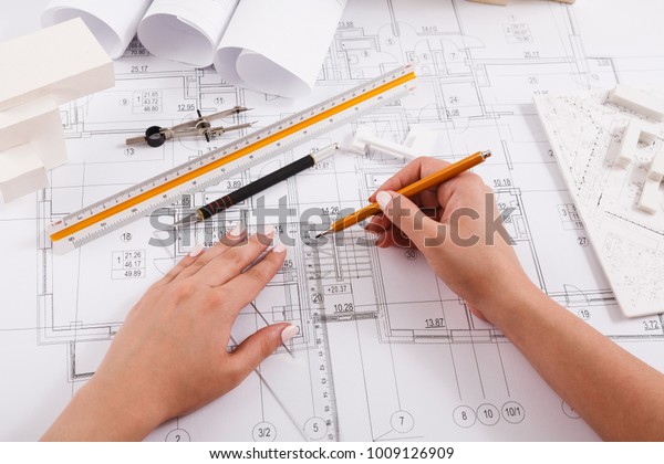 Architect\
drawing architectural project. Unrecognizable designer hands\
working with building blueprint, copy\
space