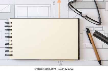 Architect engineer blank notebook, project blueprints background. Real estate design, construction site office concept.