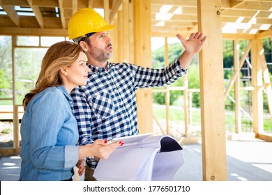 Architect or engineer with blueprints meeting with owner of building house on construction site
