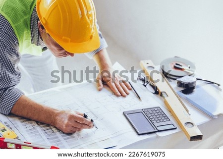 Architect Engineer Builder, Building Designer working with floorplan at Construction Site.