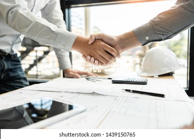 Architekten und Ingenieurinnen und Bauarbeiter schütteln sich nach Abschluss einer Vereinbarung auf der Baustelle, Erfolgskonzept für Zusammenarbeit und Teamwork die Hände 