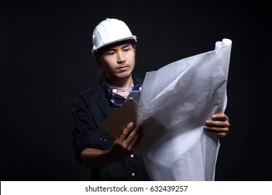 Architect Engineer In Dark Blue Shirt White Hard Hat And Blueprints Roll Check With Tablet, Studio Lighting Black Background Copy Space, Rim Light From Back
