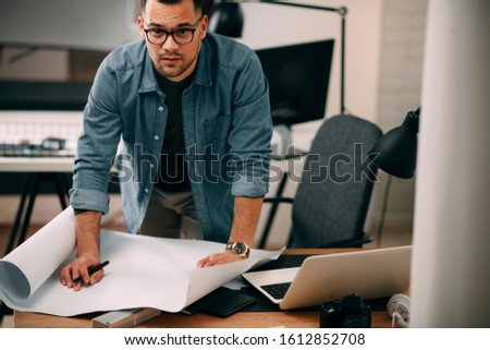 
Architect Engineer Design Working Planning Concept.
Portrait of a smiling young businessman working on blueprints at the office.