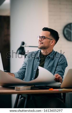 Architect Engineer Design Working Planning Concept.
Portrait of a smiling young businessman working on blueprints at the office.