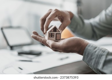 Architect engineer hands hold and protect mini house model on blueprint.  Sell, Protect House, cost planning design and construction concept.