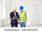 Architect, engineer or interior designer showing worker new apartment plan, realtor consulting builder in making real estate renovation, repair investment and apartment construction, wearing hardhats