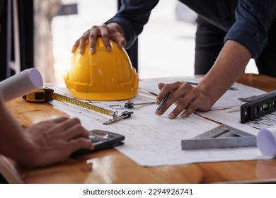 Architect and Engineer working with blueprints for architectural plan, engineer sketching a construction project, green energy concept