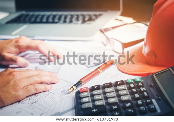 Architect or engineer working in office\
on blueprint. Architects workplace , blueprints, ruler, helmet and\
divider. Construction concept. Engineering\
tools