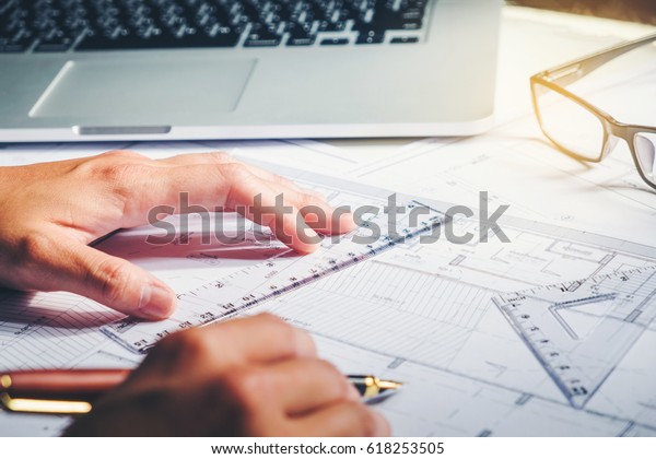 Architect or engineer working in office\
on blueprint. Architects workplace , blueprints, ruler, helmet and\
divider. Construction concept. Engineering\
tools