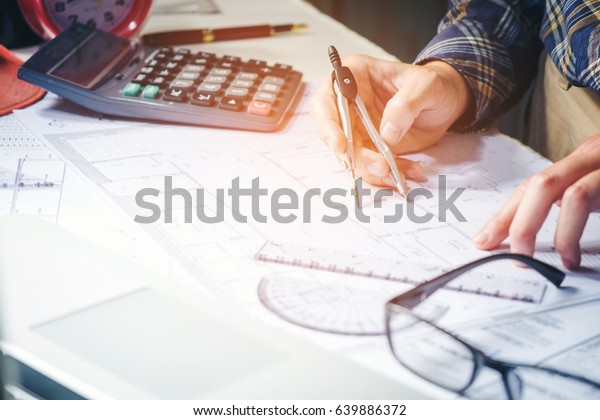 Architect or engineer working in office
on blueprint. Architects workplace , blueprints, ruler, helmet and
divider. Construction concept. Engineering
tools