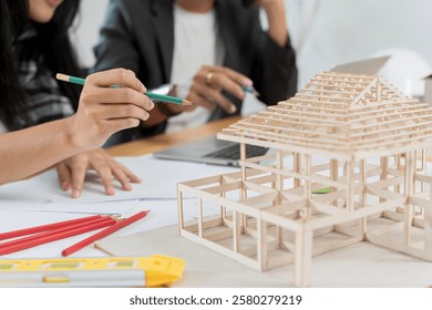 Architect explaining project plan to clients. Confident businesswoman holding architectural model in office, House structural model. Data working and tablet laptop.