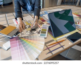 An Architect (Interior designer) working while drawing illustration with material sample  tablet computer. Home design with smart device, modern technology concept.