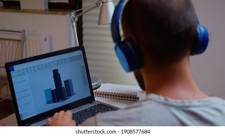 Architect looking at building model on laptop late night time in home office. Industrial employee studying prototype idea on personal computer showing cad software on device display working overtime