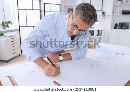 Architect making engineering drawing at table in office