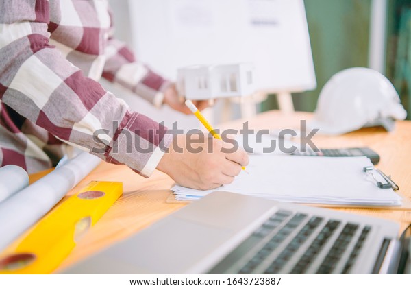 architect man with Architectural plans Laptop,\
calculator pencil pen and ruler on the table, Concept architects,\
engineer compass equipment on the desk with a blueprint in the\
office,Selective\
Focus