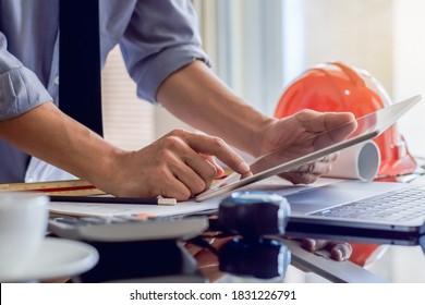 Architect man or male engineer work on digital tablet with blue print and laptop computer on the desk at office. 