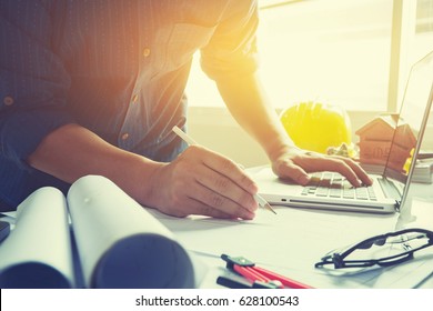 architect man working with laptop and blueprints,engineer inspection in workplace for architectural plan,sketching a construction project ,selective focus,Business concept vintage color