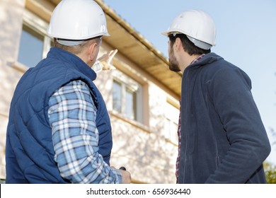 Architect And Mason Inspecting The Exterior Of The House