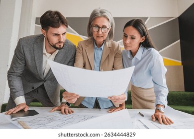 Architect mature woman with young team engineers holding working with blueprints for architectural plan, engineer sketching a construction project, green energy concept