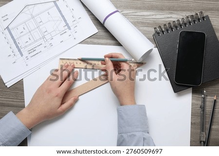 Architect with pencil and set square ruler working on project at wooden table, top view