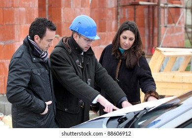 Architect reviewing a building plan with his clients - Powered by Shutterstock