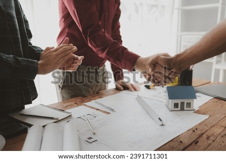 The architect shake hands with the foreman as the job was agreed upon, An engineer contracts with a company to construct a building, Engineer and architect check hand as work is finalized.