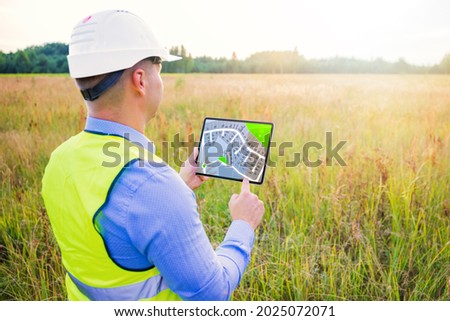 Architect using digital tablet with blueprints and surveying a new residential housing building land plot