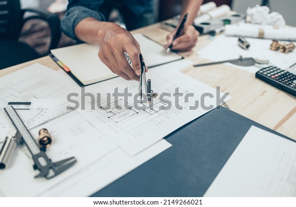 Architect using\
divider compass working on blueprint and make a note on book.\
Construction concept. Engineering\
tools