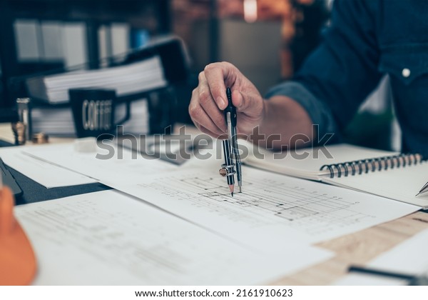 Architect using\
divider compass working on blueprint and make a note on book.\
Construction concept. Engineering\
tools