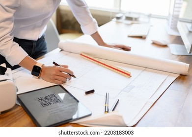 Architect Woman Inspects Detail Of Building In The Construction Drawing Paper Or Blueprint On Desk Office With Technology QR Code Scan For 3D Digital Model In Tablet, Technology In Architect Jobs.