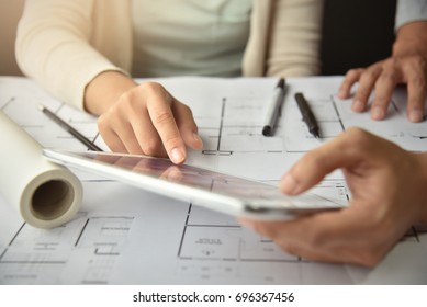 Architect Woman And Man Hands Brainstorming For New Interior Design Renovation Projects. Creative Designer Team Discussing And Working On Digital Tablet, Blueprint, Construction Drawing Plan At Office