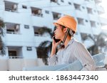 architect woman use mobile phone call with enginner or project manager between survey and checking at site construction. Architect woman hold blueprint.