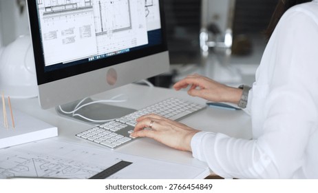 Architect working at desktop computer, checking blueprints and design plans for a new engineering project. Business and architecture concept