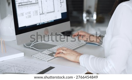 Architect working at desktop computer, checking blueprints and design plans for a new engineering project. Business and architecture concept