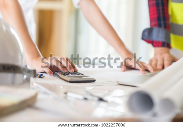 Architect working on blueprint. Architects
workplace - architectural project, blueprints, ruler, calculator,
laptop and divider compass. Construction concept. Engineering
tools,selective focus