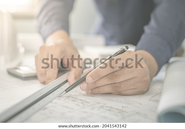 Architect working on blueprint. Architects
workplace - architectural project, blueprints, ruler, calculator,
laptop and divider compass. Construction concept. Blue print is
fake only for stock
photo.