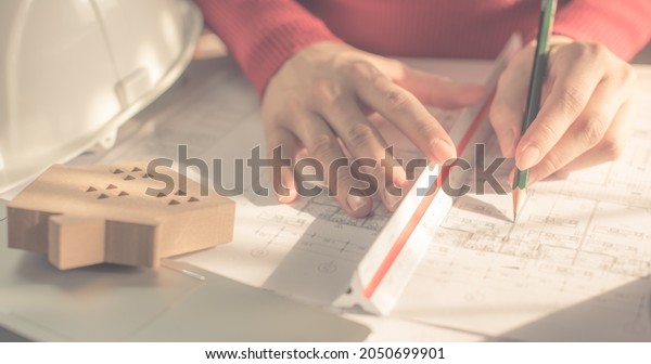 Architect working on blueprint. Architects\
workplace - architectural project, blueprints, ruler, calculator,\
laptop and divider compass. Construction concept. Blue print is\
fake only for stock\
photo.