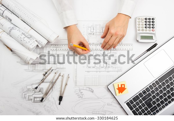 Architect working\
on blueprint. Architects workplace - architectural project,\
blueprints, ruler, calculator, laptop and divider compass.\
Construction concept. Engineering\
tools