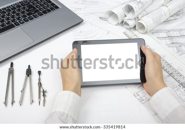 Architect working on blueprint. Architects\
workplace - architectural project, blueprints, ruler, tablet pc,\
laptop and divider compass. Construction concept. Engineering\
tools. Copy space for\
text.