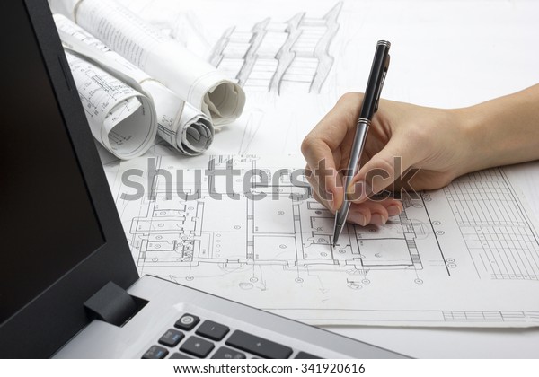 Architect working on blueprint. Architects\
workplace - architectural project, plan, laptop, pen. Construction\
concept. Engineering\
tools